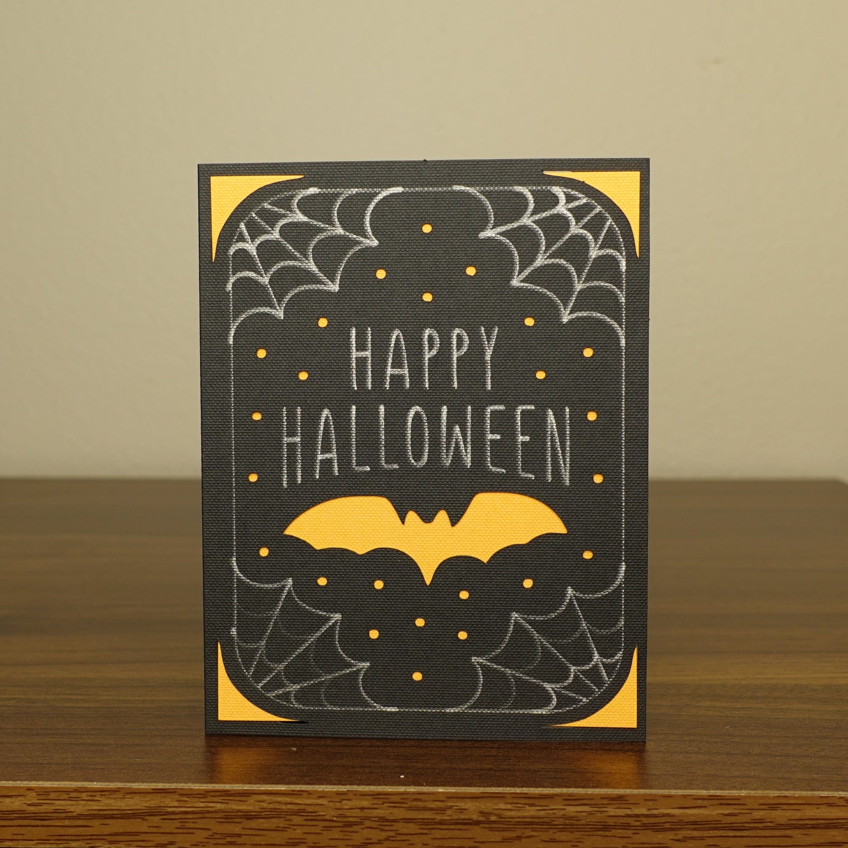 black, white, and orange card with a bat and the words "Happy Halloween"